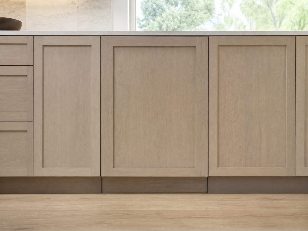 A panel-ready wine cellar hinged on the left, sitting flush in a run of base cabinets so only the toe kick and the seam show.